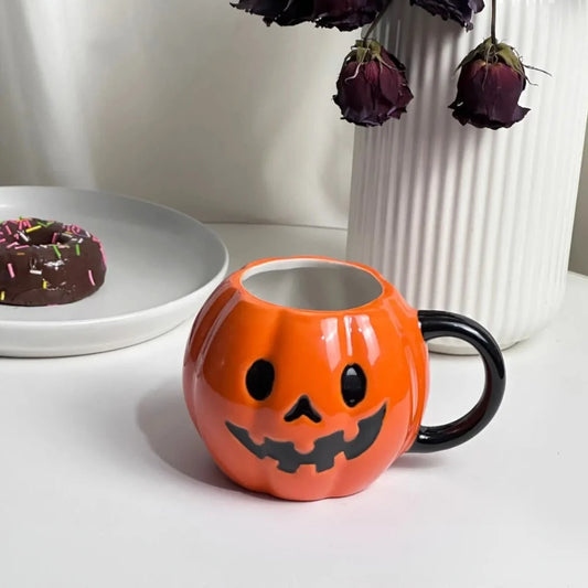 Halloween Mug Pumpkin in front of a vase and a table with a donut on it