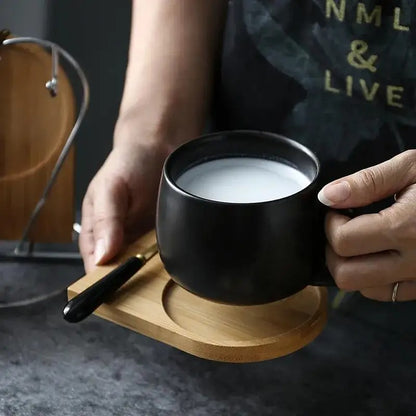 Person holding a Black Ceramic Mug with milk inside with a wooden tray underneath