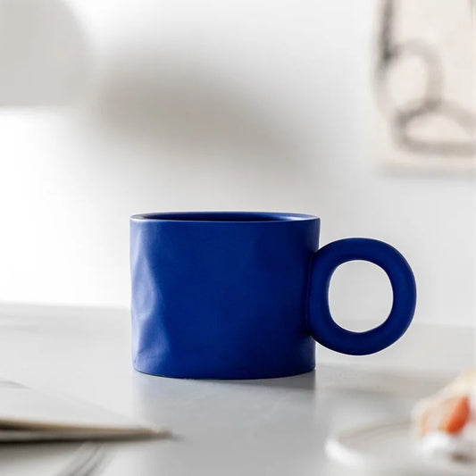 Blue Ceramic Cup on a gray table in front of a white background