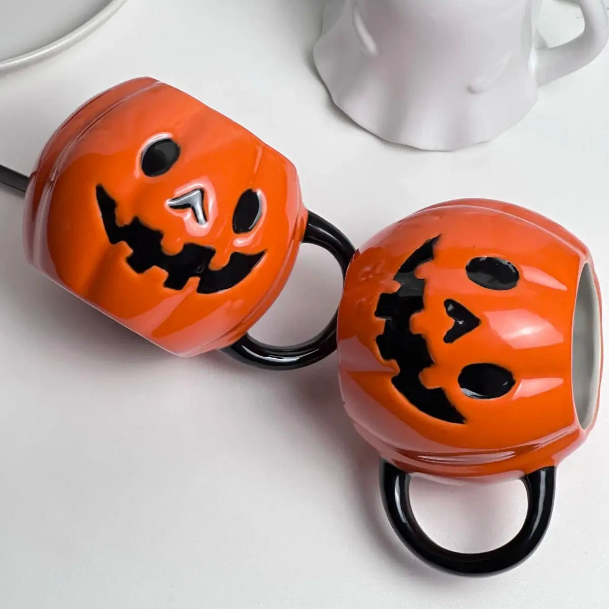 Two Pumpkin Halloween mugs on a white table